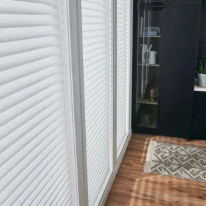 White sheer shades on a hallway window beside a dark built-in shelving unit